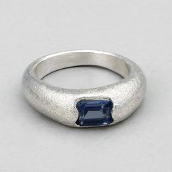 Silver ring with a blue gemstone on a gray background