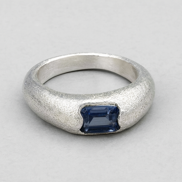 Silver ring with a blue gemstone on a gray background