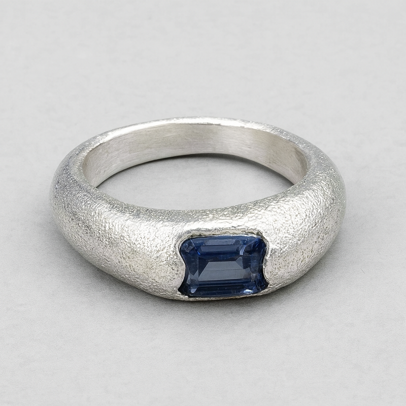 Silver ring with a blue gemstone on a gray background
