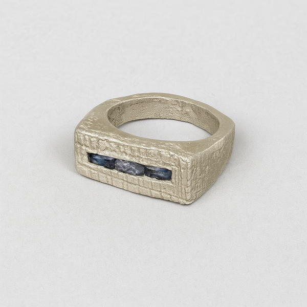 Silver ring with embedded stones on a light gray background