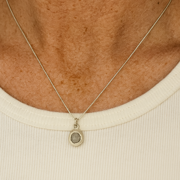 Necklace with a pendant worn by a person on a beige background
