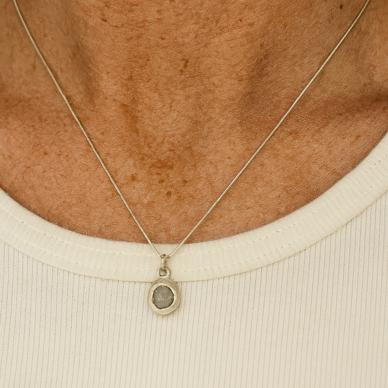 Necklace with a pendant worn by a person on a beige background