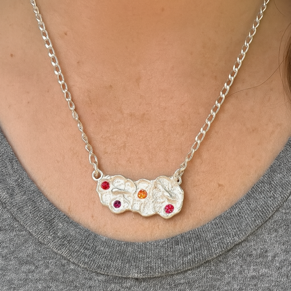 Silver necklace with colorful stones worn by a person