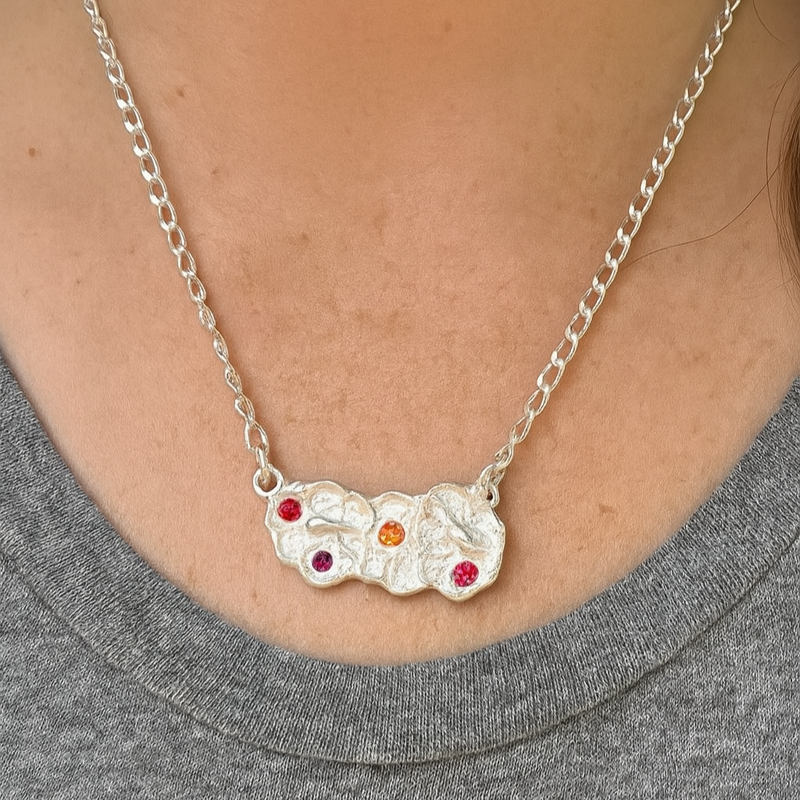 Silver necklace with colorful stones worn by a person