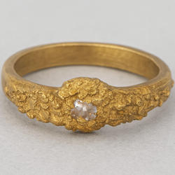 Gold ring with a diamond on a light gray background