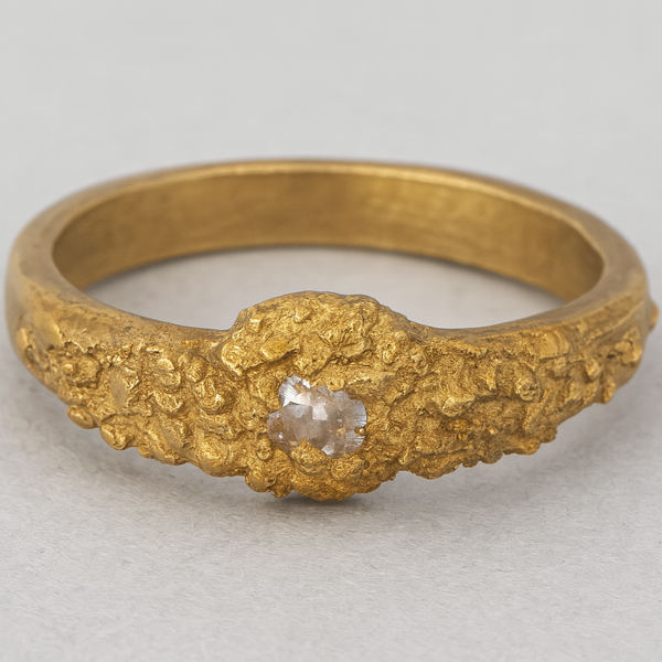 Gold ring with a diamond on a light gray background