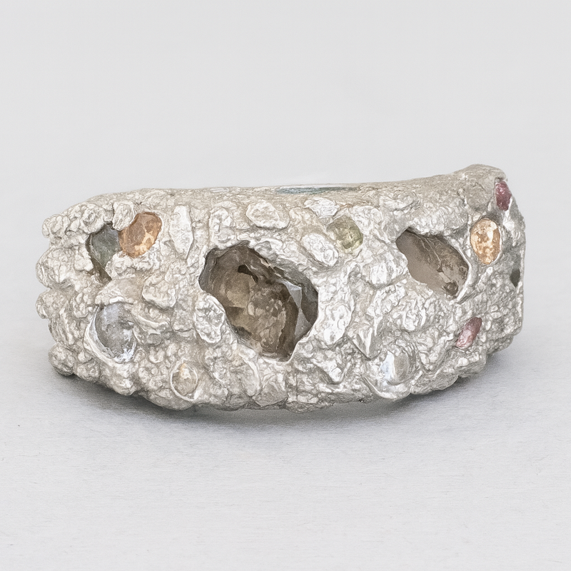 Silver ring with embedded stones on a light gray background