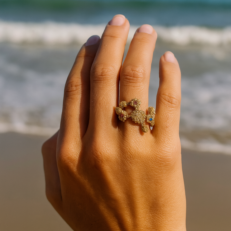 Hand wearing a ring with a beach and ocean in the background