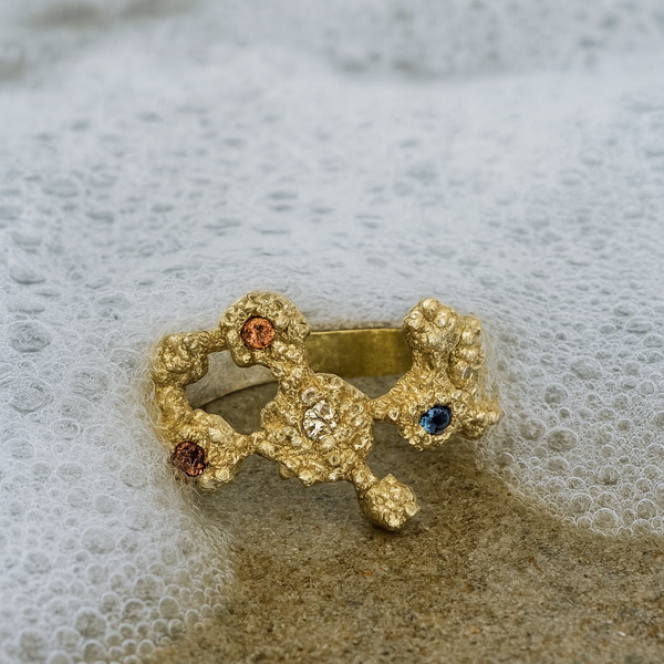 Gold ring with gemstones on a sandy surface