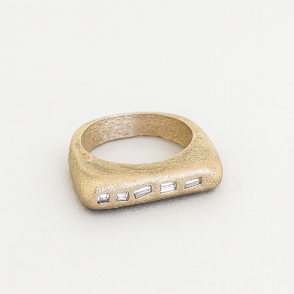 Gold ring with embedded stones on a light gray background