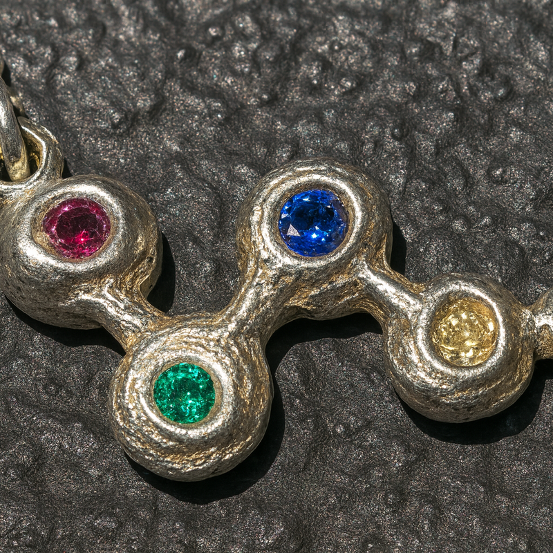 Necklace with four colored gemstones on a textured dark surface
