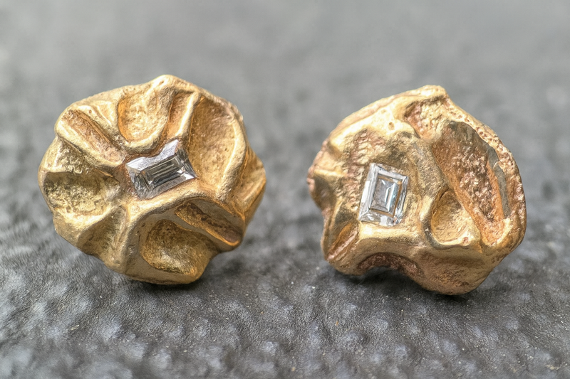 Gold earrings with diamond accents on a gray background