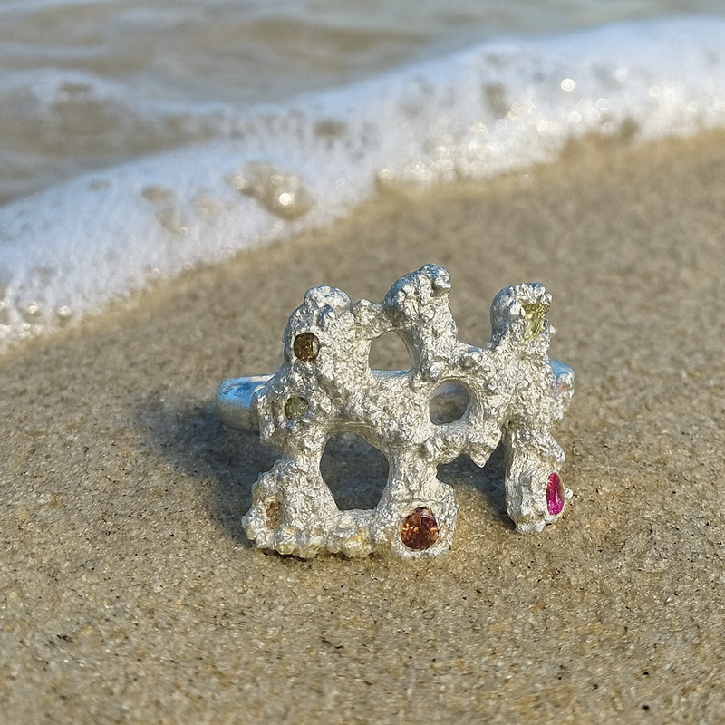 Decorative ring with gemstones on a sandy beach