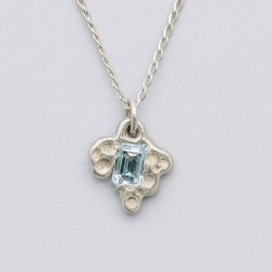 Silver necklace with a pendant featuring a blue gemstone on a light gray background