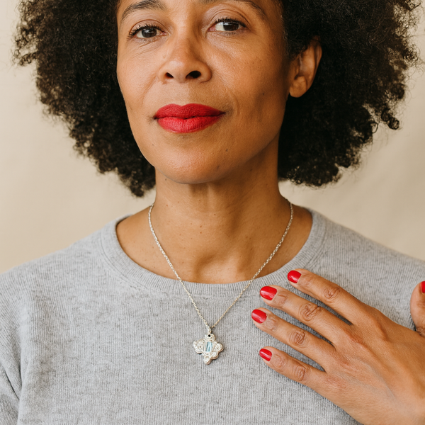 Woman with red lipstick and a gray shirt against a beige background