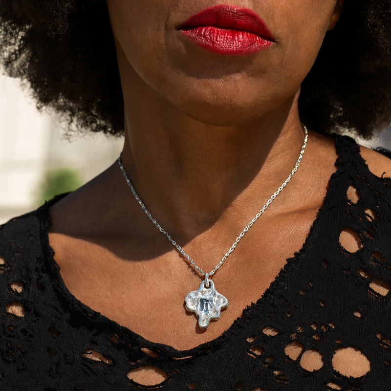 Close-up of a person wearing a black lace top and a necklace with a pendant.