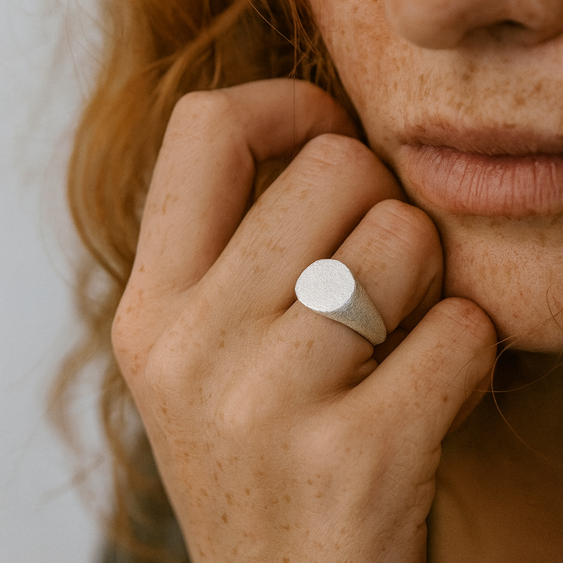 Close-up of a person wearing a silver ring on a neutral background