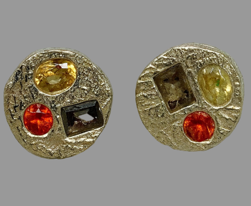 Pair of round earrings with colorful gemstones on a light gray background