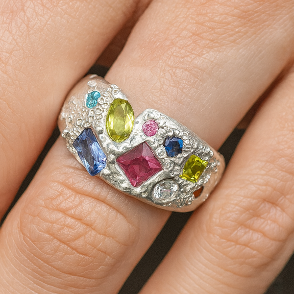 Ring with multicolored gemstones on a finger