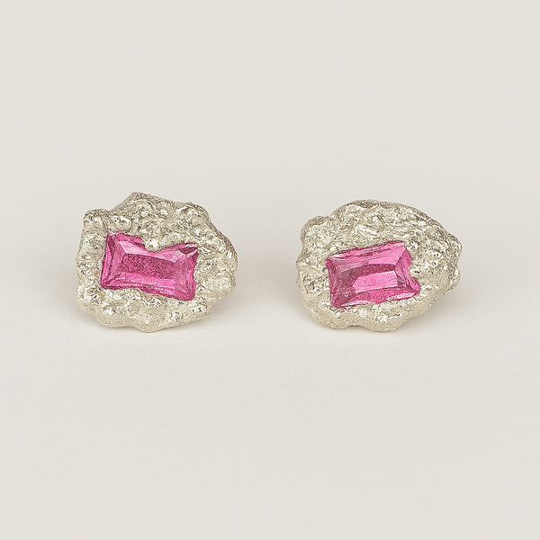 Pair of earrings with pink gemstones on a light gray background