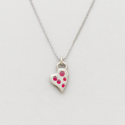Silver heart-shaped pendant necklace with red stones on a light gray background
