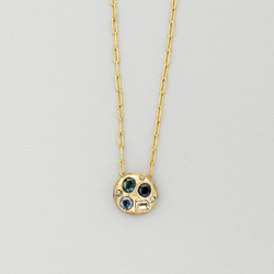 Gold necklace with a pendant featuring three colored stones on a gray background