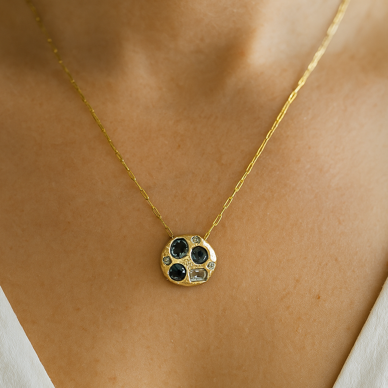 Gold necklace with a floral pendant on a person wearing a white top.