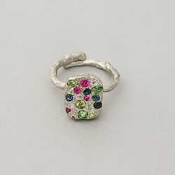 Silver ring with multicolored gemstones on a light gray background