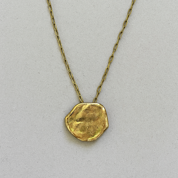 Gold necklace with a unique pendant on a light gray background