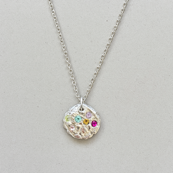Silver necklace with a round pendant featuring colorful gemstones on a light gray background