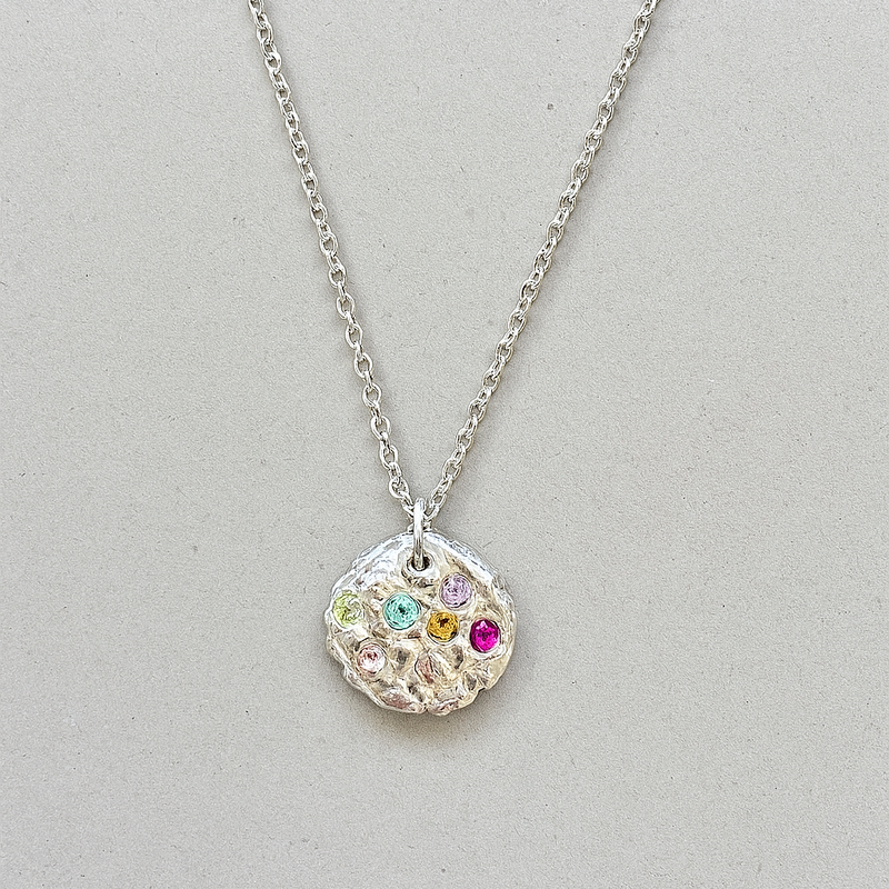 Silver necklace with a round pendant featuring colorful gemstones on a light gray background