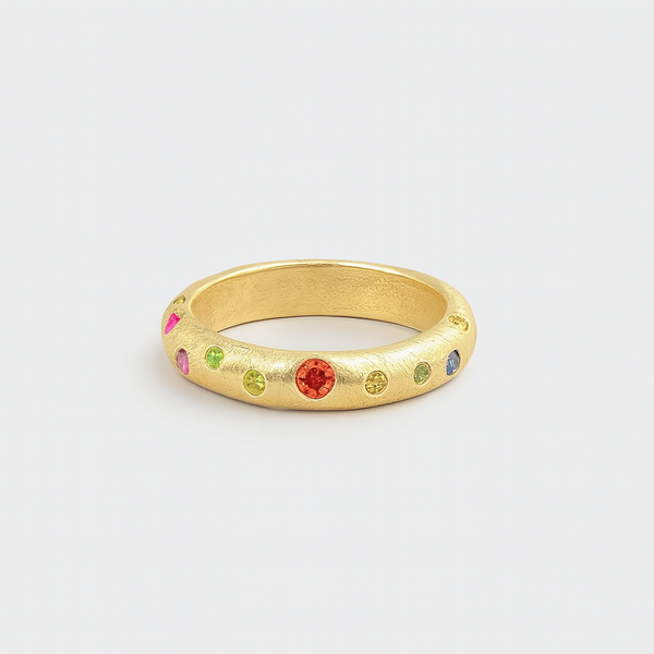 Gold ring with colorful gemstones on a light gray background