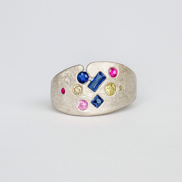 Silver ring with colorful gemstones on a light gray background
