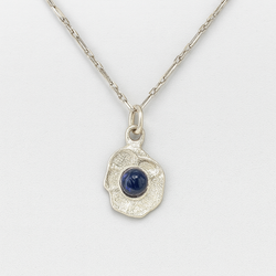 Silver pendant with a blue gemstone on a white background