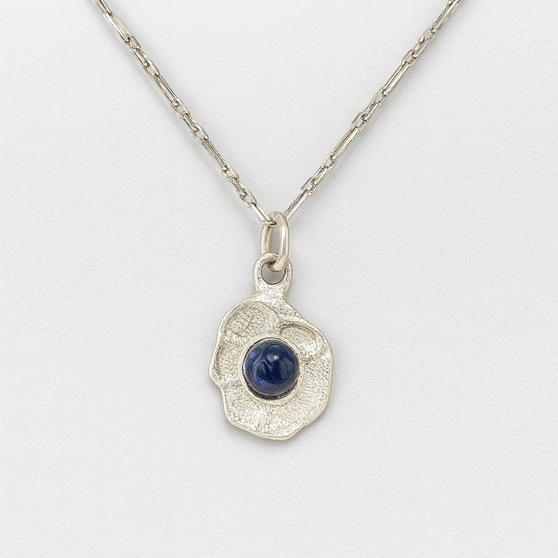 Silver pendant with a blue gemstone on a white background