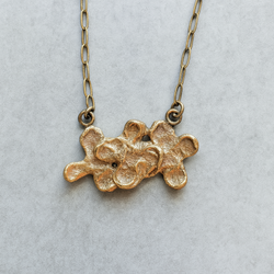 Gold necklace with a textured pendant on a light gray background