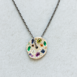 Necklace with a colorful gemstone pendant on a light gray background