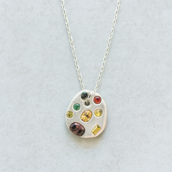 Necklace with a colorful gemstone pendant on a light gray background