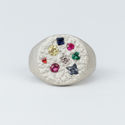 Silver ring with multicolored gemstones on a light gray background