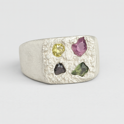 Silver ring with multicolored gemstones on a light gray background