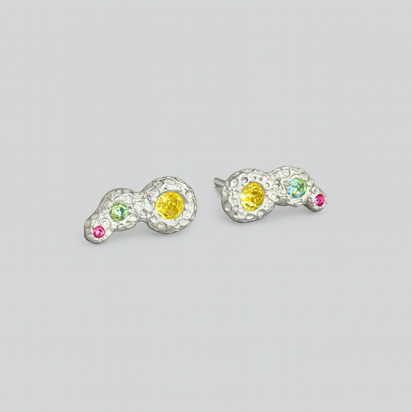 Pair of earrings with colorful gemstones on a light gray background