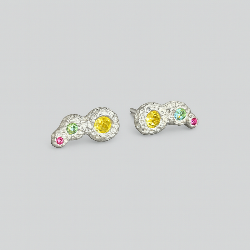 Pair of earrings with colorful gemstones on a light gray background