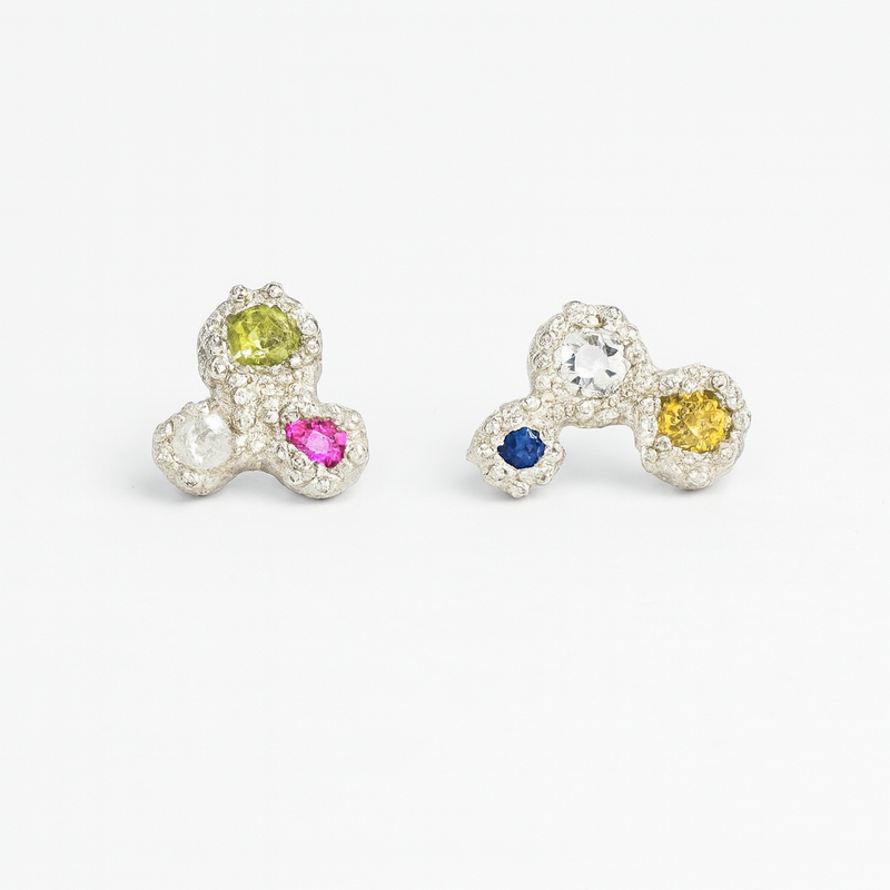 Pair of bow-shaped earrings with colored gemstones on a white background