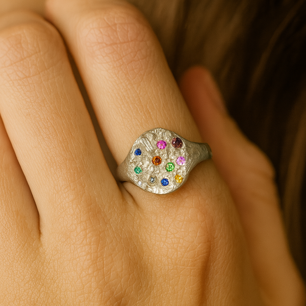 Close-up of a hand wearing a ring with multicolored gemstones.