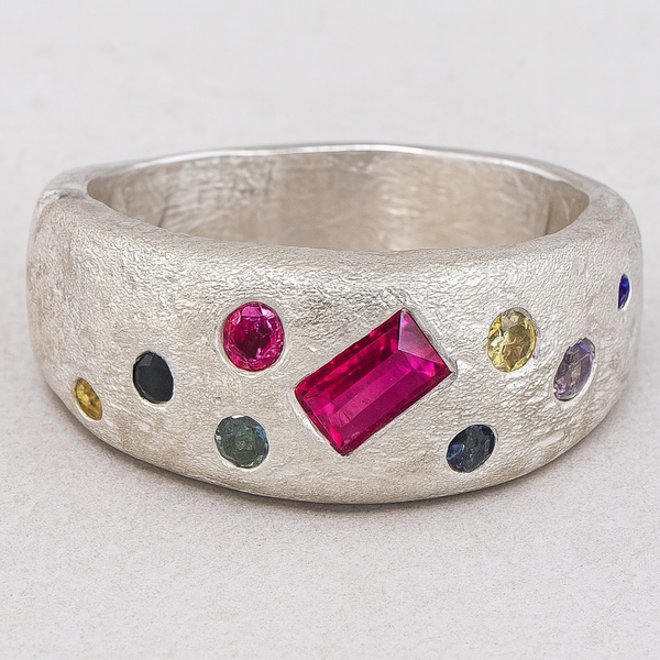 Silver ring with colorful gemstones on a light gray background