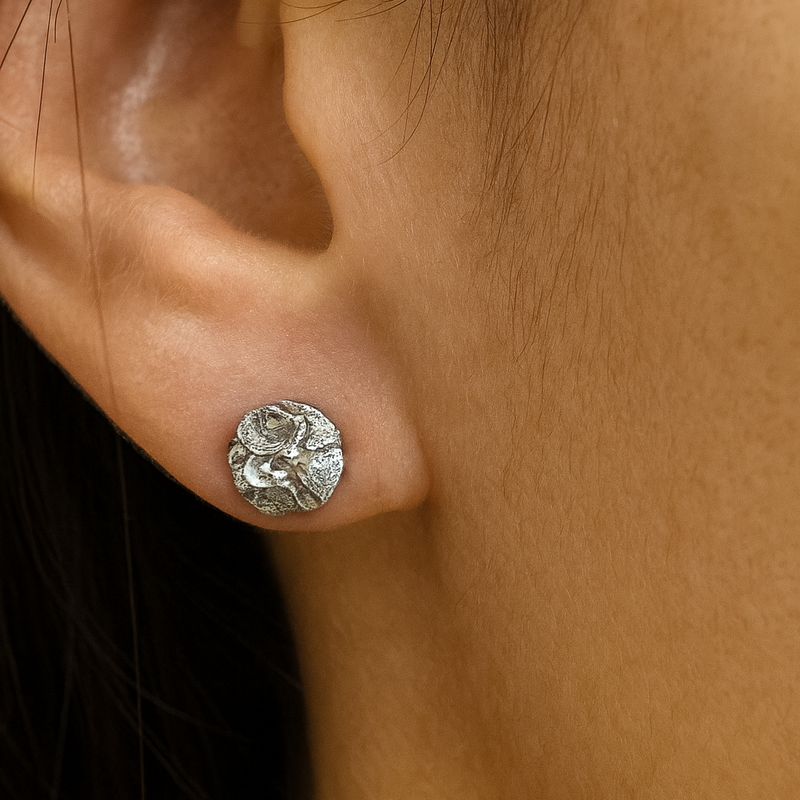 Close-up of a silver stud earring on an ear