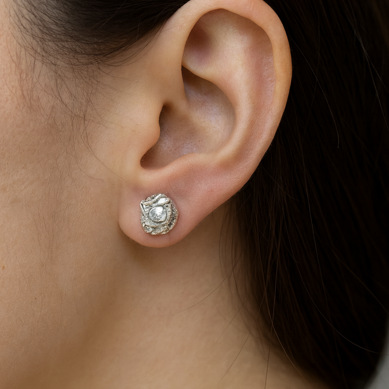 Close-up of an ear wearing a silver earring with a decorative design.