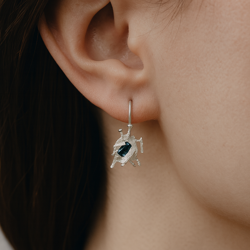 Close-up of an earring worn on an ear with a neutral background