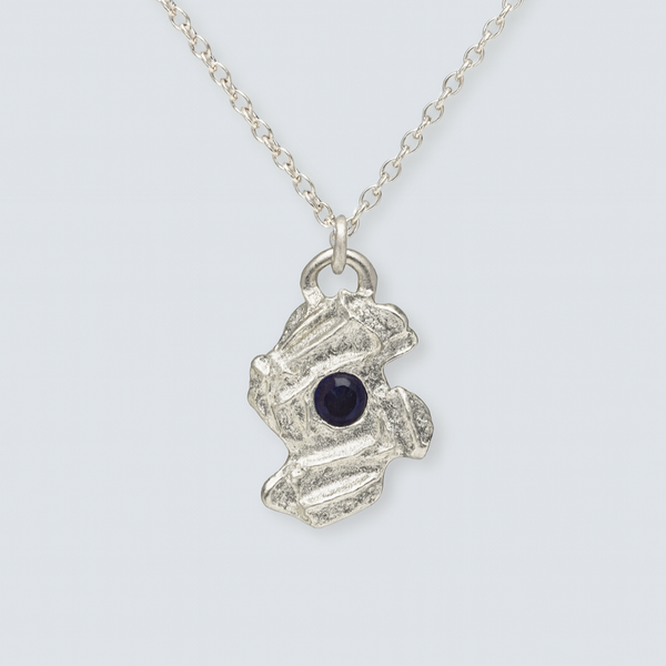 Silver necklace with a textured pendant featuring a dark gemstone on a light gray background
