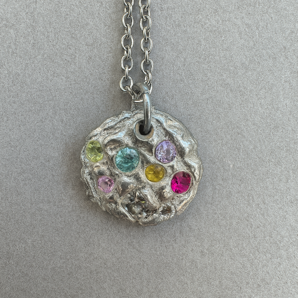 Necklace with a round pendant featuring colorful gemstones on a gray background